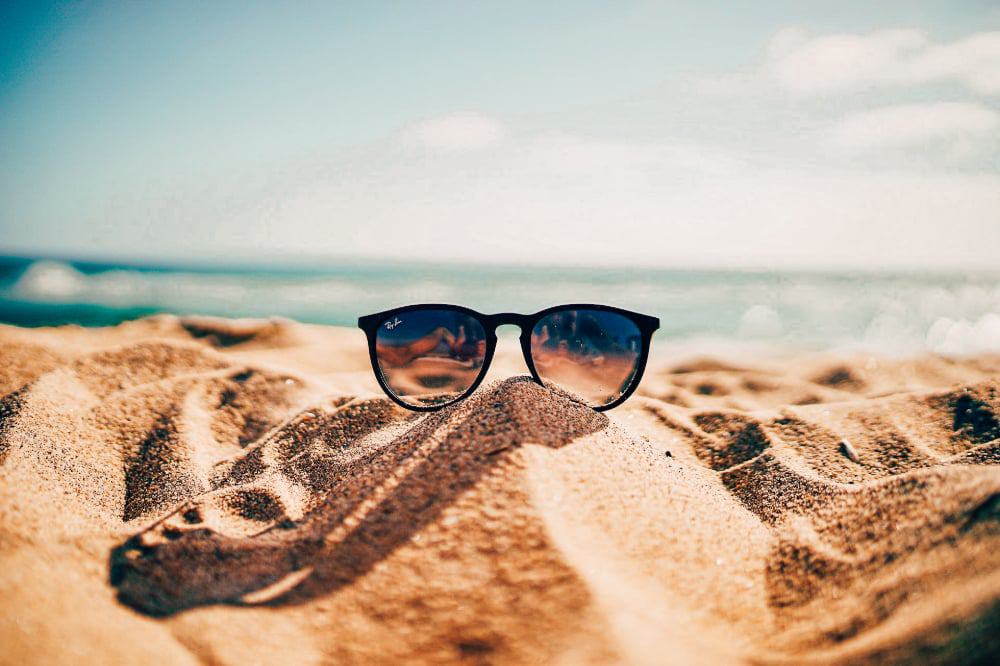 A pair of sunglasses on a sandy beach