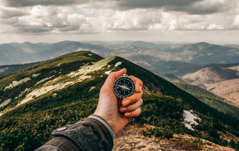 A person using a compass on top of a mountain peak