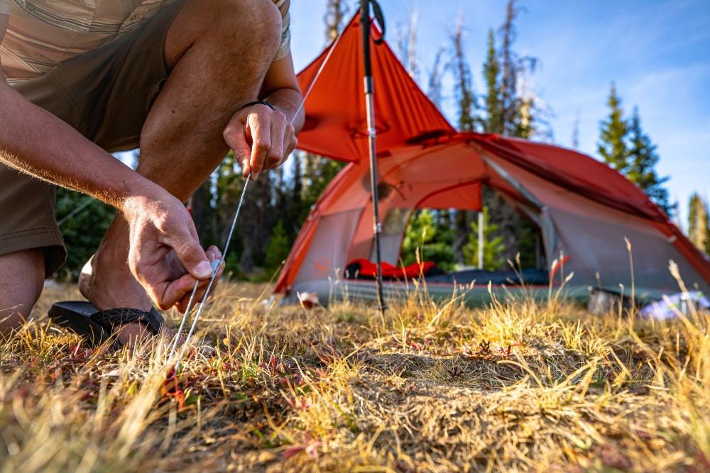 Man pitching the Big Agnes Copper Spur tent by connecting the guyline to the stakes