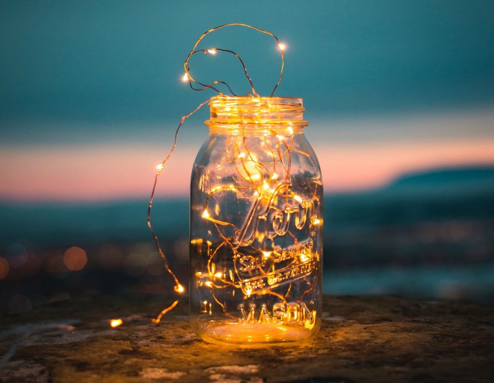 A jar of fairy lights on a rock ledge at sunset that will light up all your nighttime romantic camping activities.